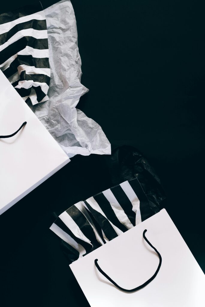 Stylish black and white shopping bags with striped tissue paper, perfect for holiday sales promotions.